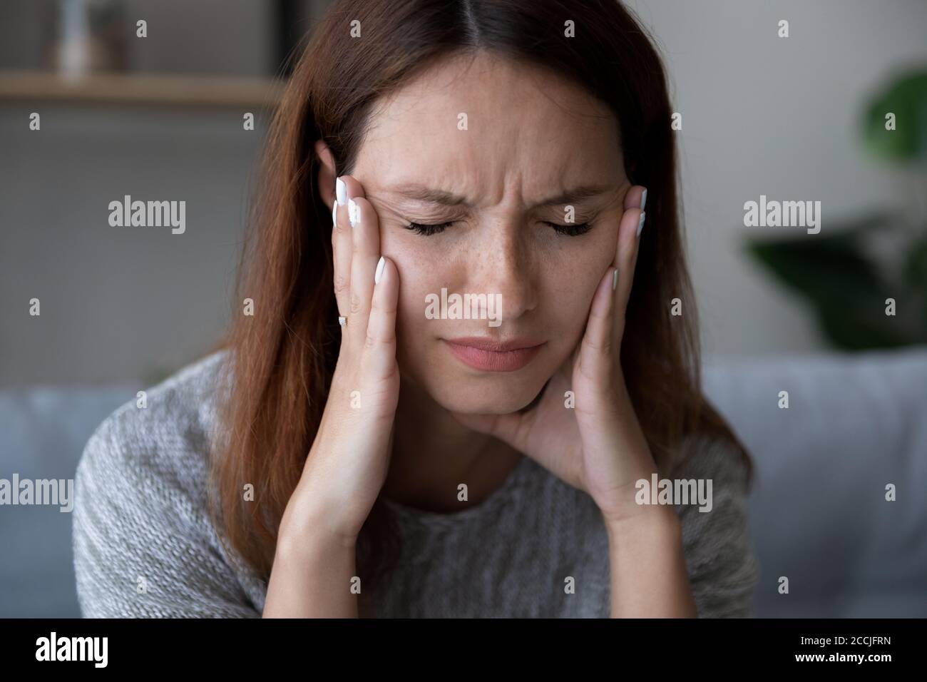Tired unwell woman suffer from headache at home Stock Photo