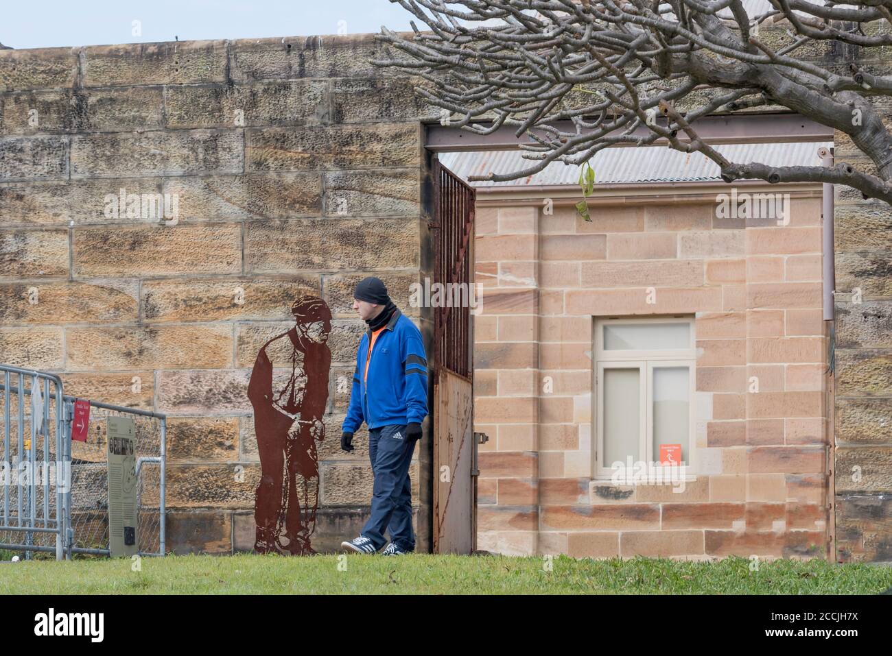 A local guide at a former prisoners area on Cockatoo Island wearing a knitted cap or Beanie. He is beside a silhouette of a Convict also wearing a cap Stock Photo