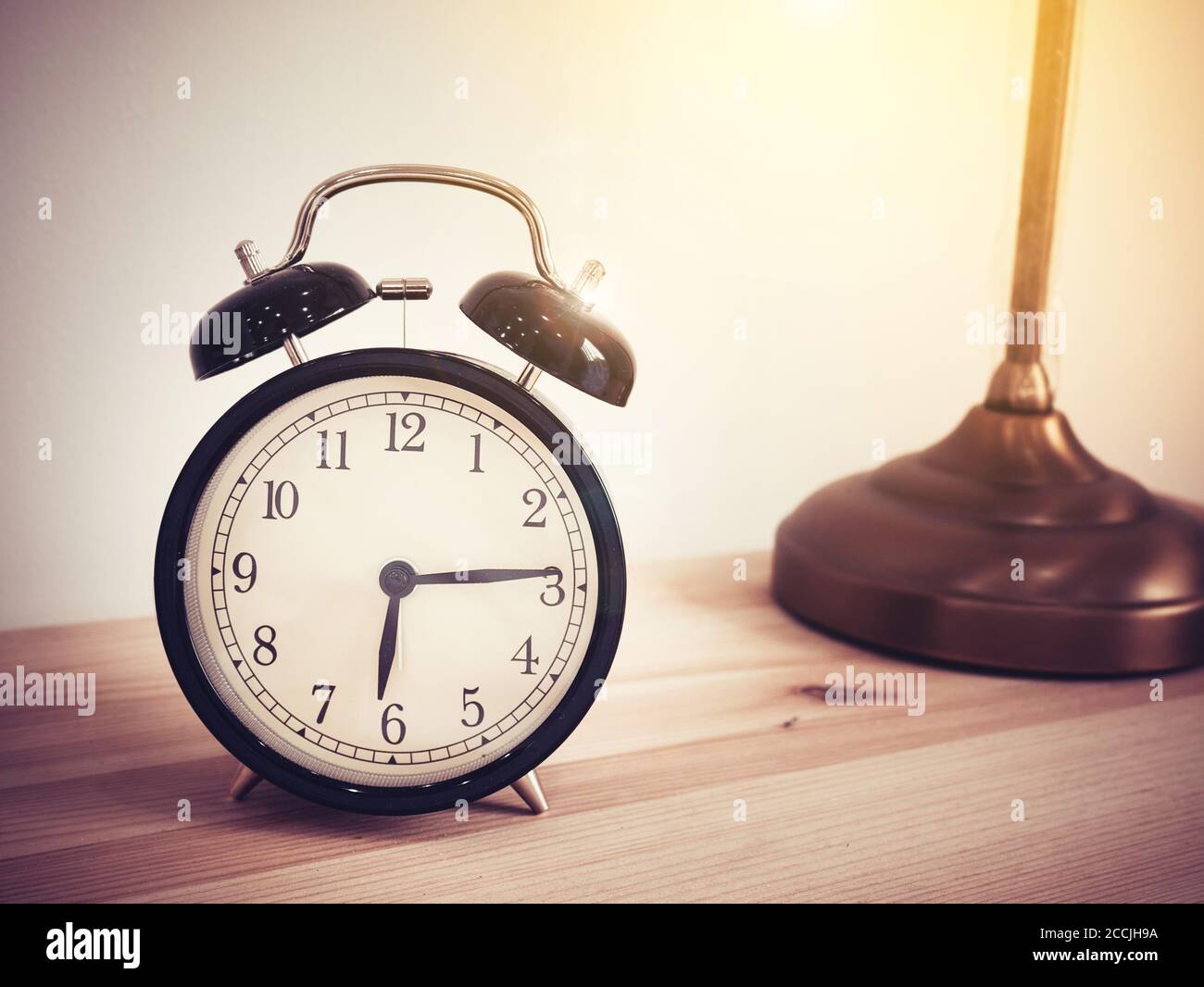 Closeup retro alarm clock on wooden table with copy space, retro style Stock Photo