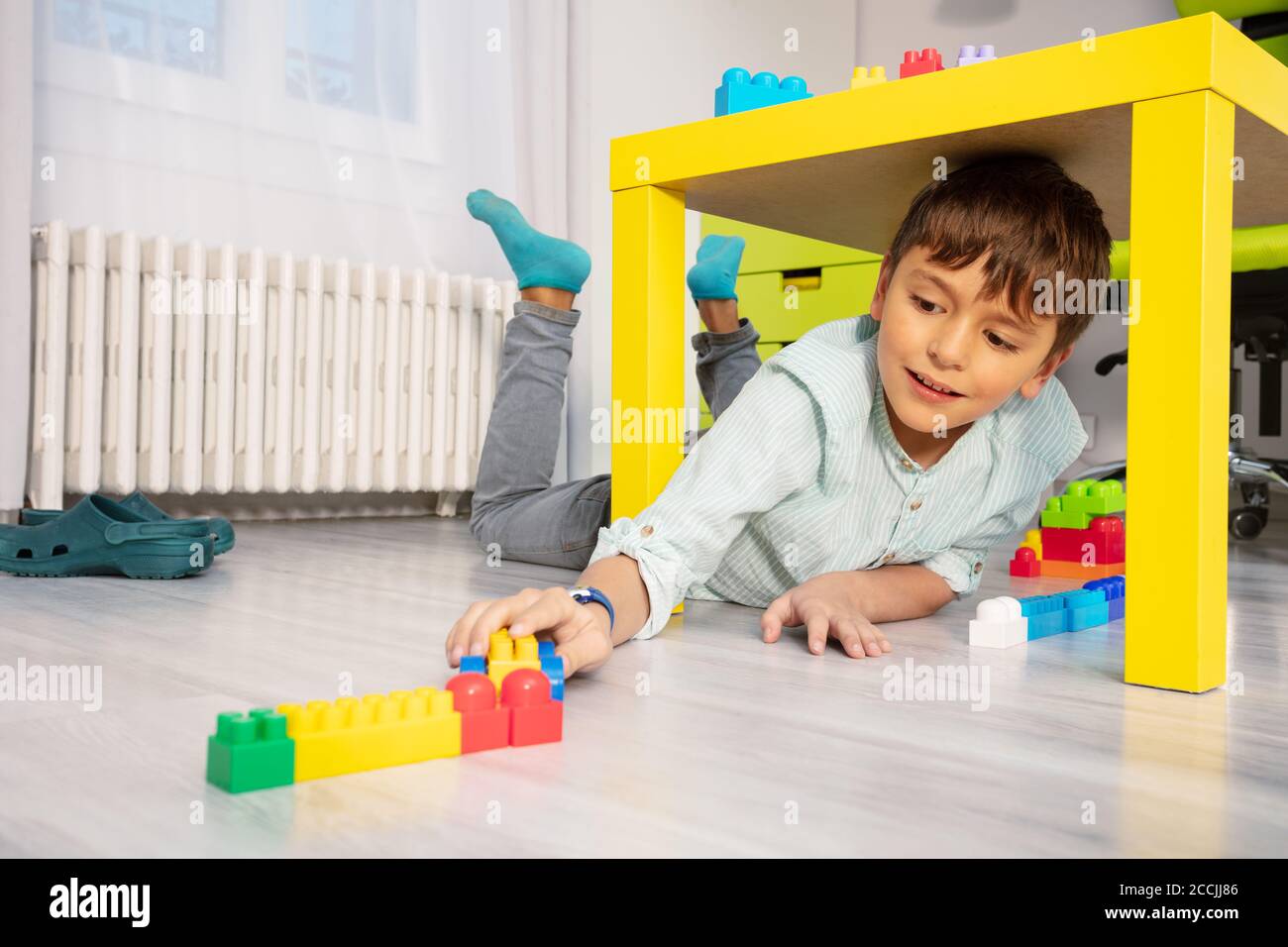 Boy play with blocks under table in kids room laying on the floor Stock Photo Alamy