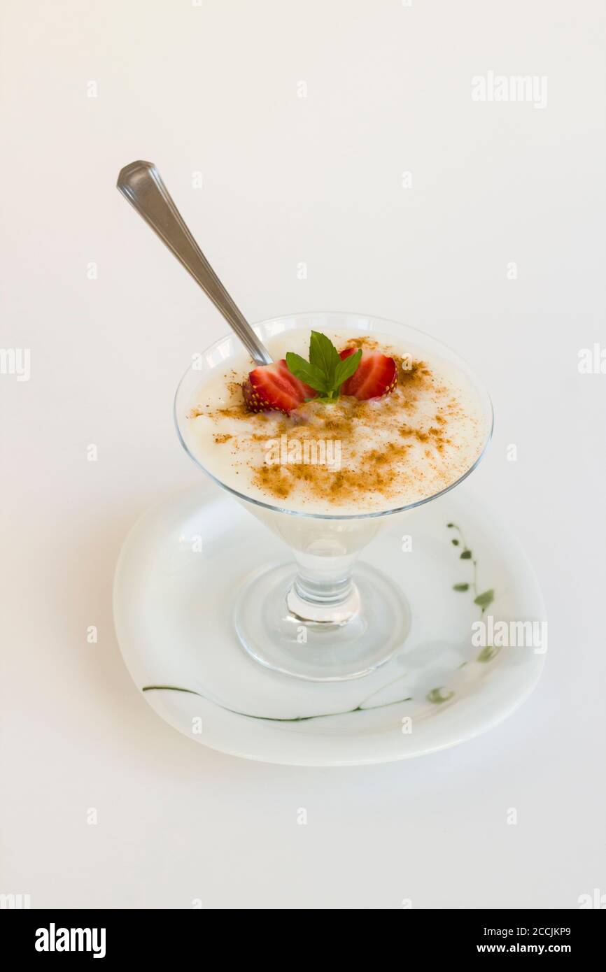 Traditional Turkish Rice Puding in stylish glass bowl with spoon on white background. Stock Photo