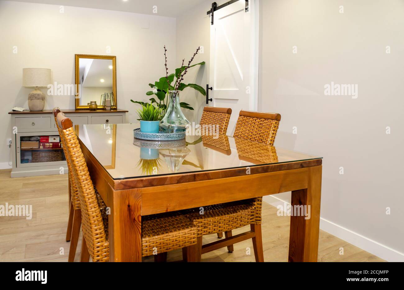 Bright dining room with a wooden table and rattan chairs. Stock Photo