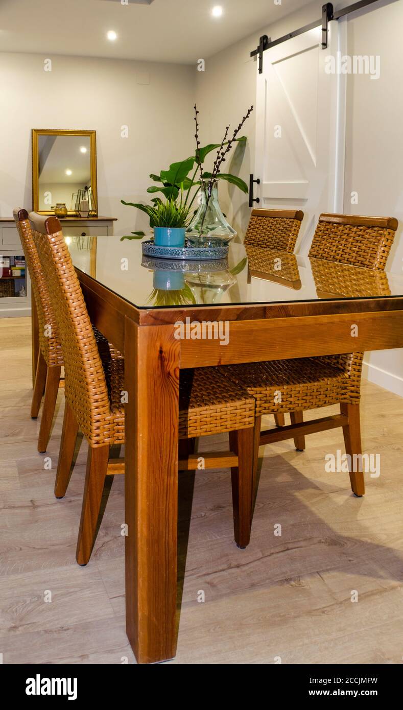 Bright dining room with a wooden table and rattan chairs. Stock Photo