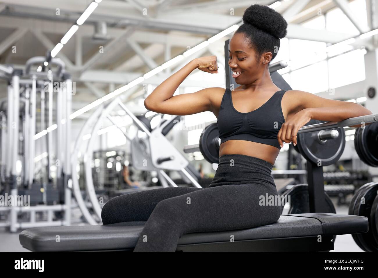 strong lady show arm muscles, sit in gym after training, happy woman in  sportswear look at her arm and smile Stock Photo - Alamy