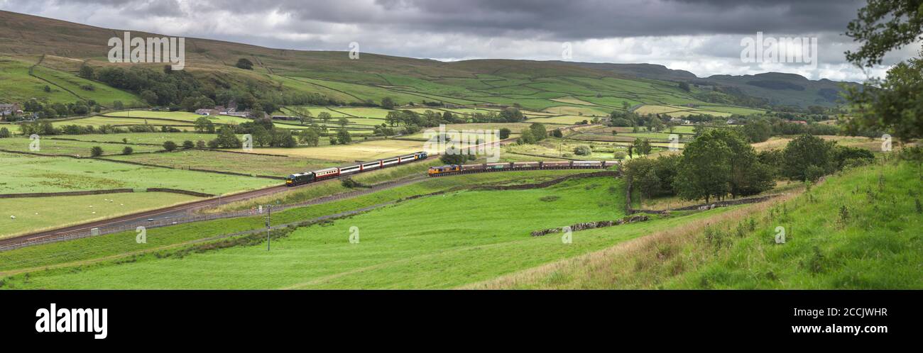 The 'Staycation Express'  train passing a GBRF freight train at Helwith bridge, in the Yorkshire Dales on the scenic Settle to Carlisle railway line Stock Photo