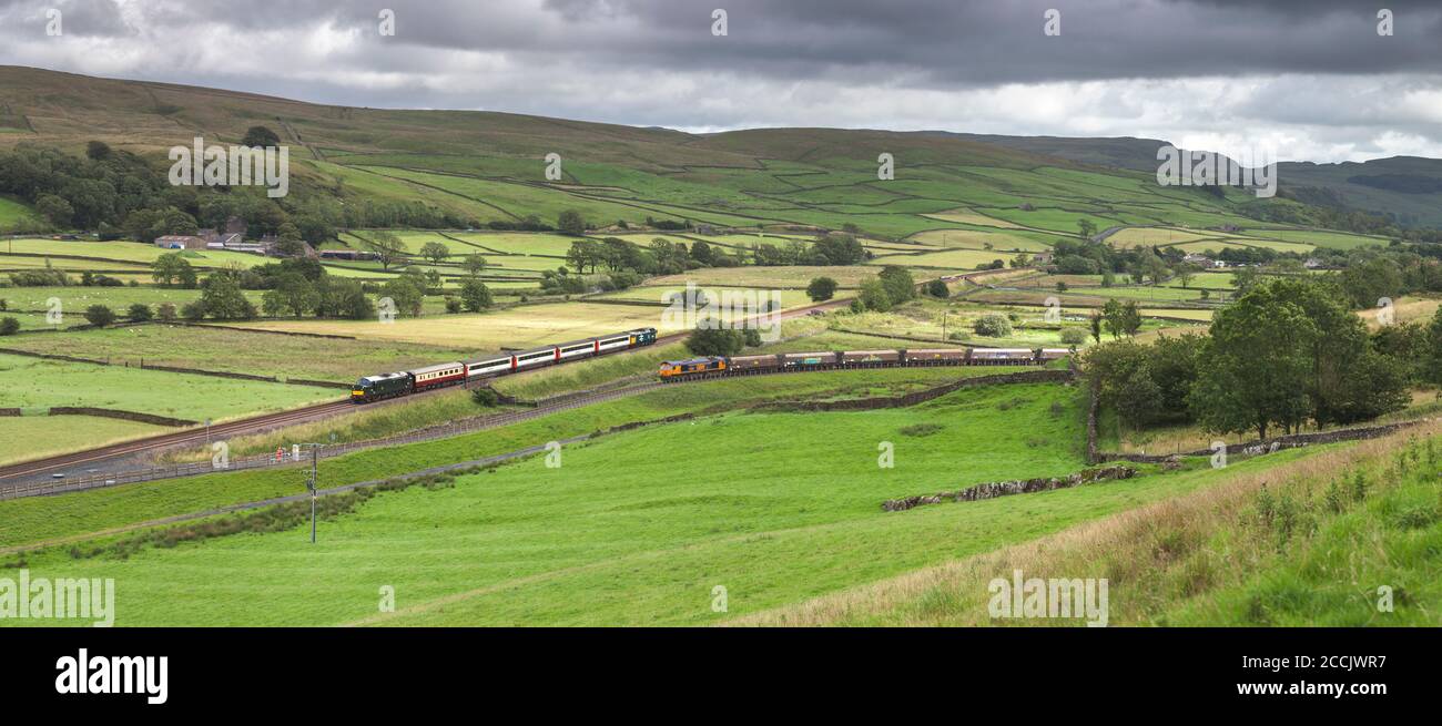 The 'Staycation Express'  train passing a GBRF freight train at Helwith bridge, in the Yorkshire Dales on the scenic Settle to Carlisle railway line Stock Photo