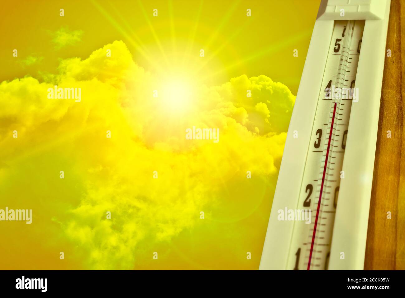 Heat wave - the concept of global warming. Summer heat. Thermometer +39°C against a hot yellow sky and sun. Stock Photo