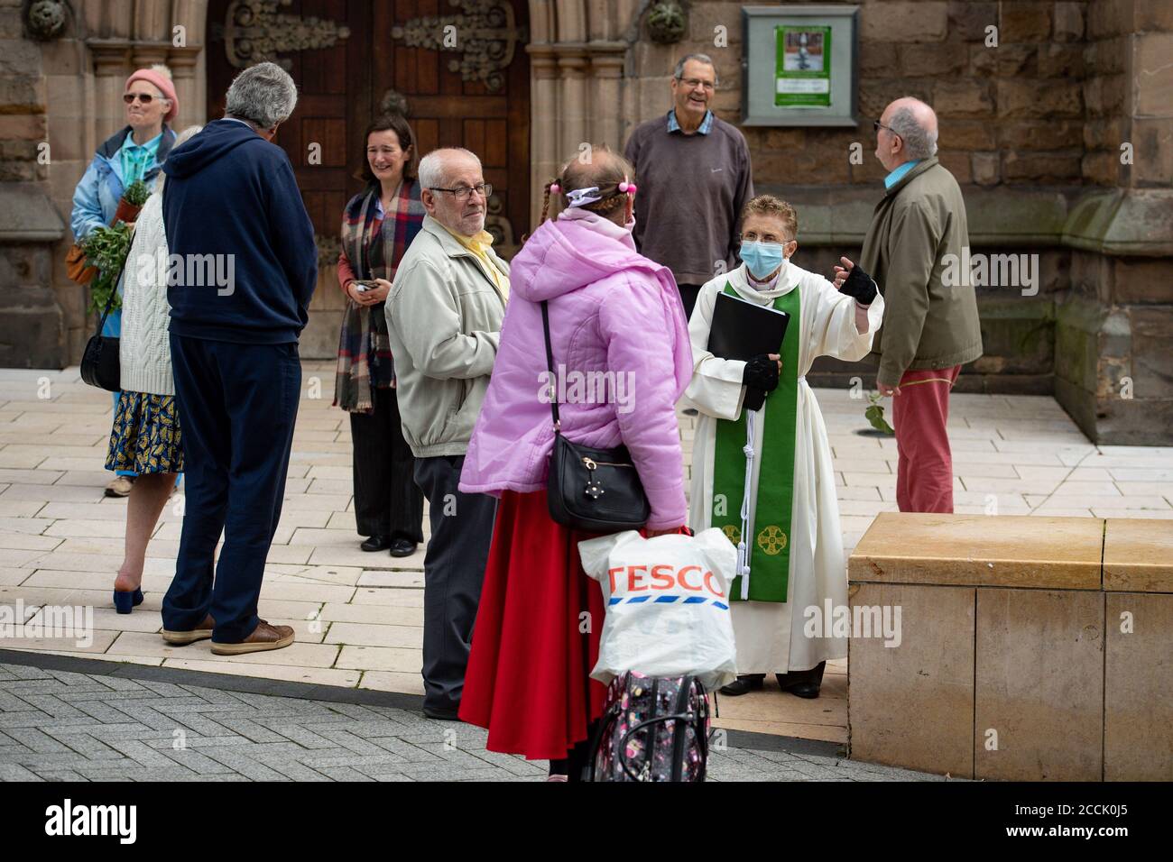 A priest wearing PPE speaks to a member of the St Martin congregation in Birmingham city centre after it was announced on Friday that the city has been added to a watch list as an 'area of enhanced support', moving it closer to localised lockdown-style restrictions if the rise in cornavirus cases continues to rise. Stock Photo