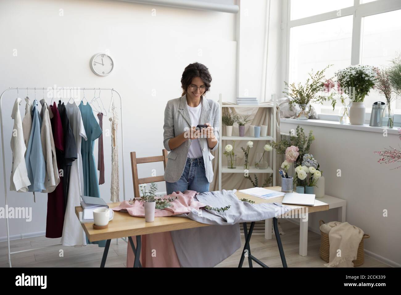 Smiling young beautiful businesswoman making photo of new clothes collection. Stock Photo