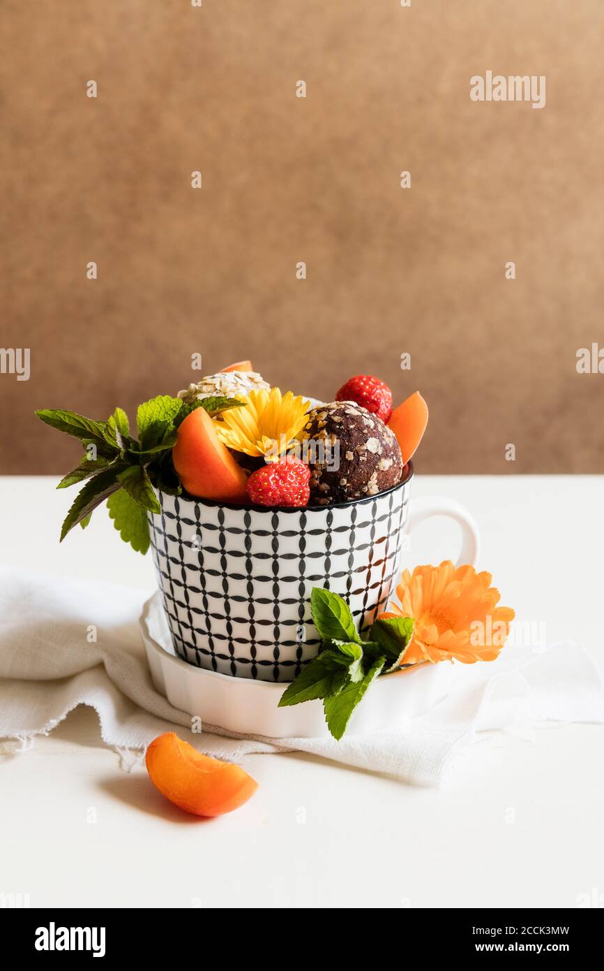 Dessert with energy balls (raw confectionery) and fresh fruits and flowers Stock Photo
