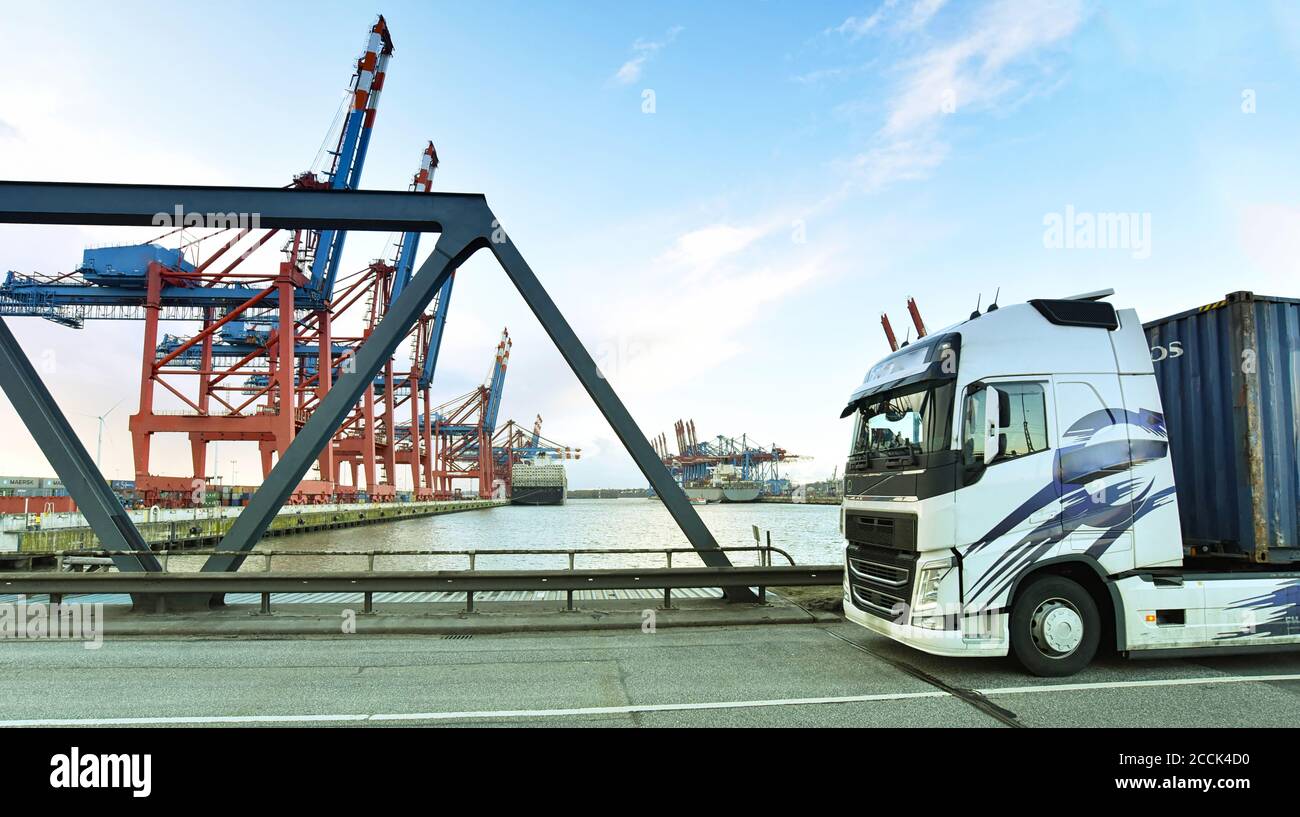 transport and traffic - trucks on the road and a terminal with ships in the background Stock Photo