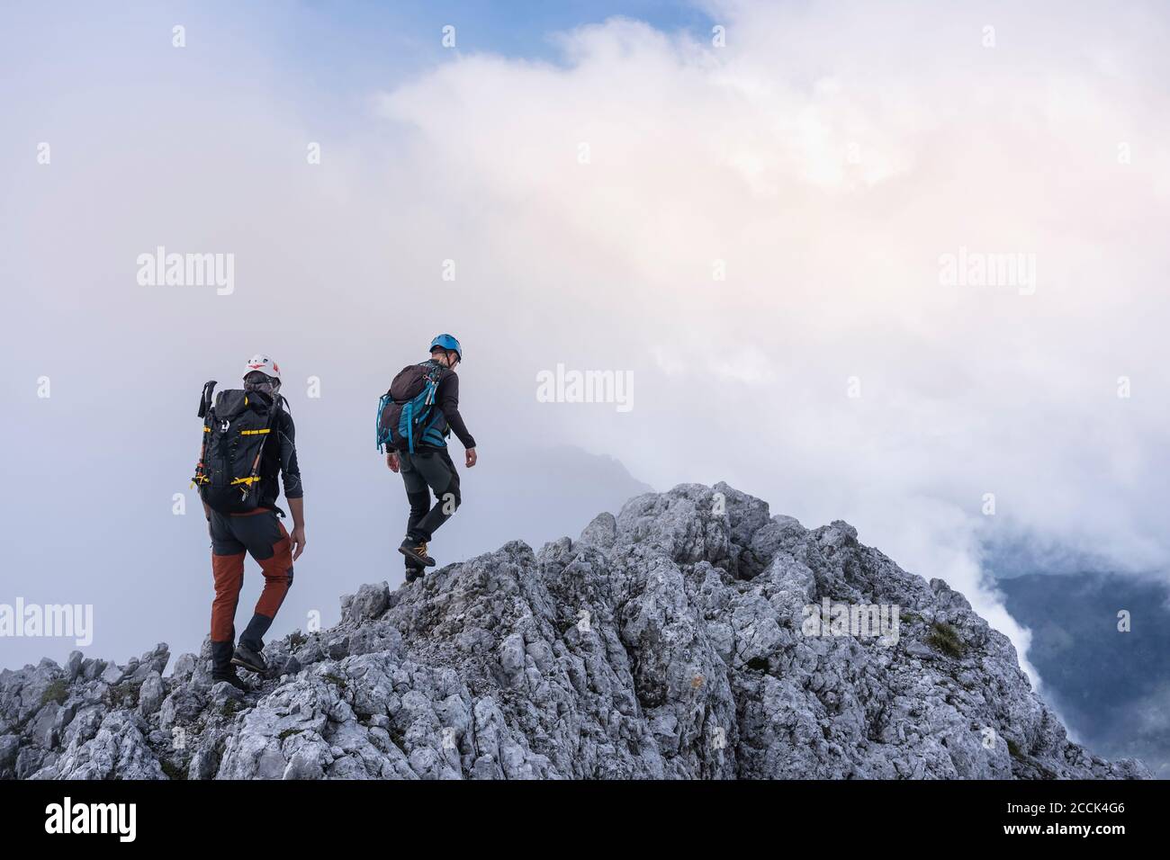 Mature males hiking on mountain against cloudy sky, Bergamasque Alps, Italy Stock Photo