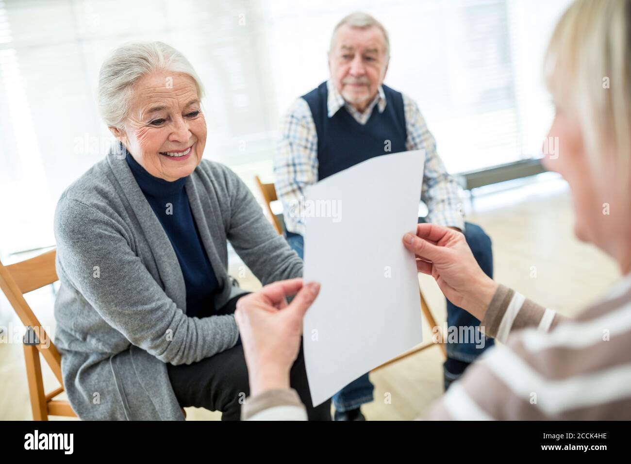 Senior woman in therapy goup on retiremnet home reading sheet of paper Stock Photo