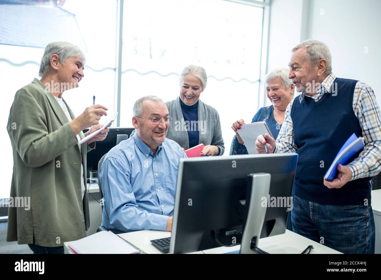 Active seniors attending computer course, watching instructor and ...