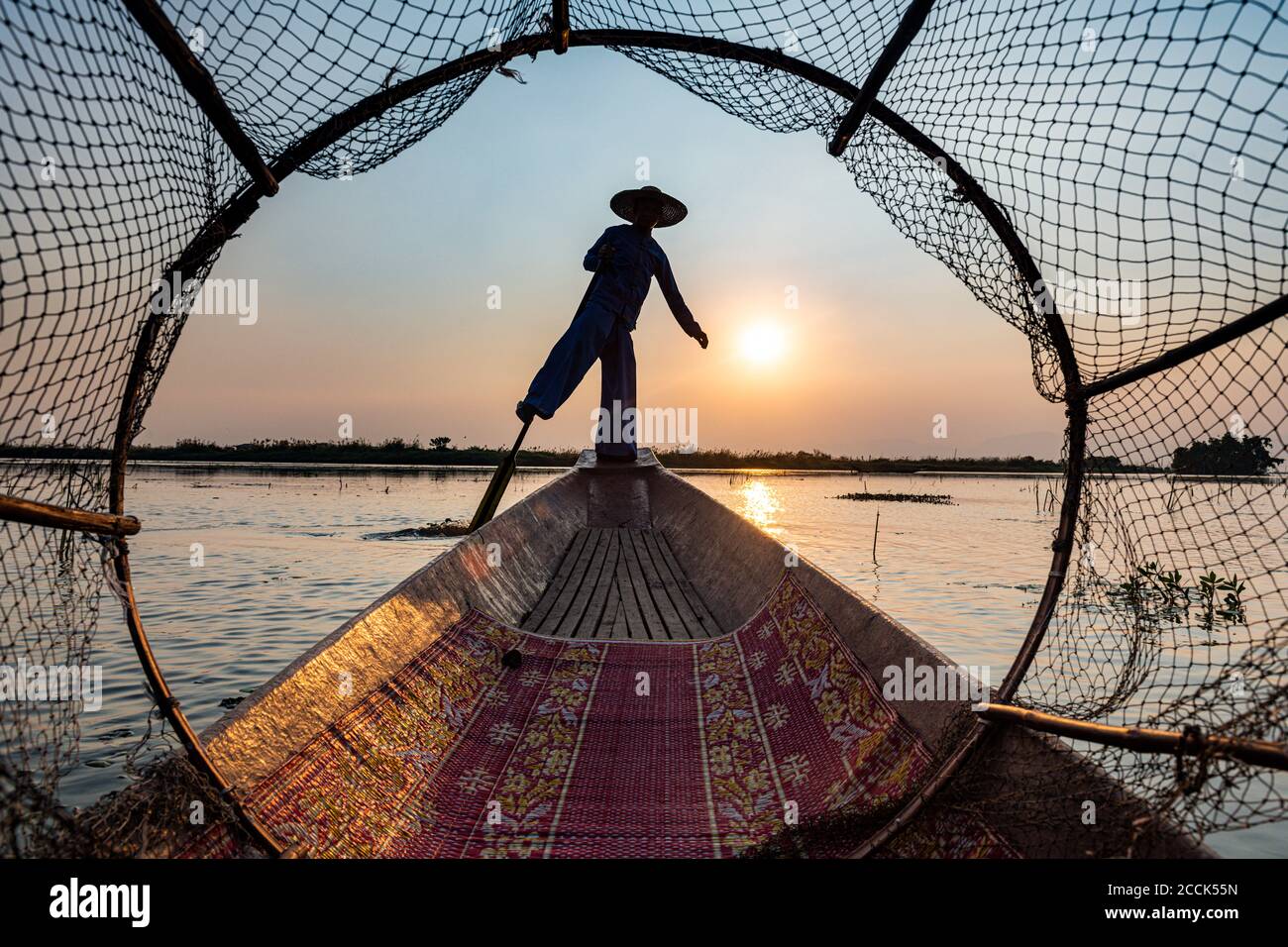 Myanmar, Shan state, Silhouette of traditional Intha fisherman on boat on Inle lake at sunset Stock Photo