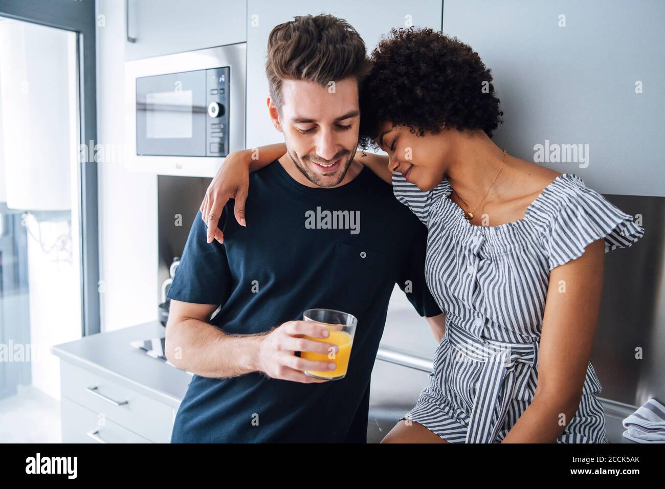 Romantic multi-ethnic couple in kitchen of penthouse Stock Photo