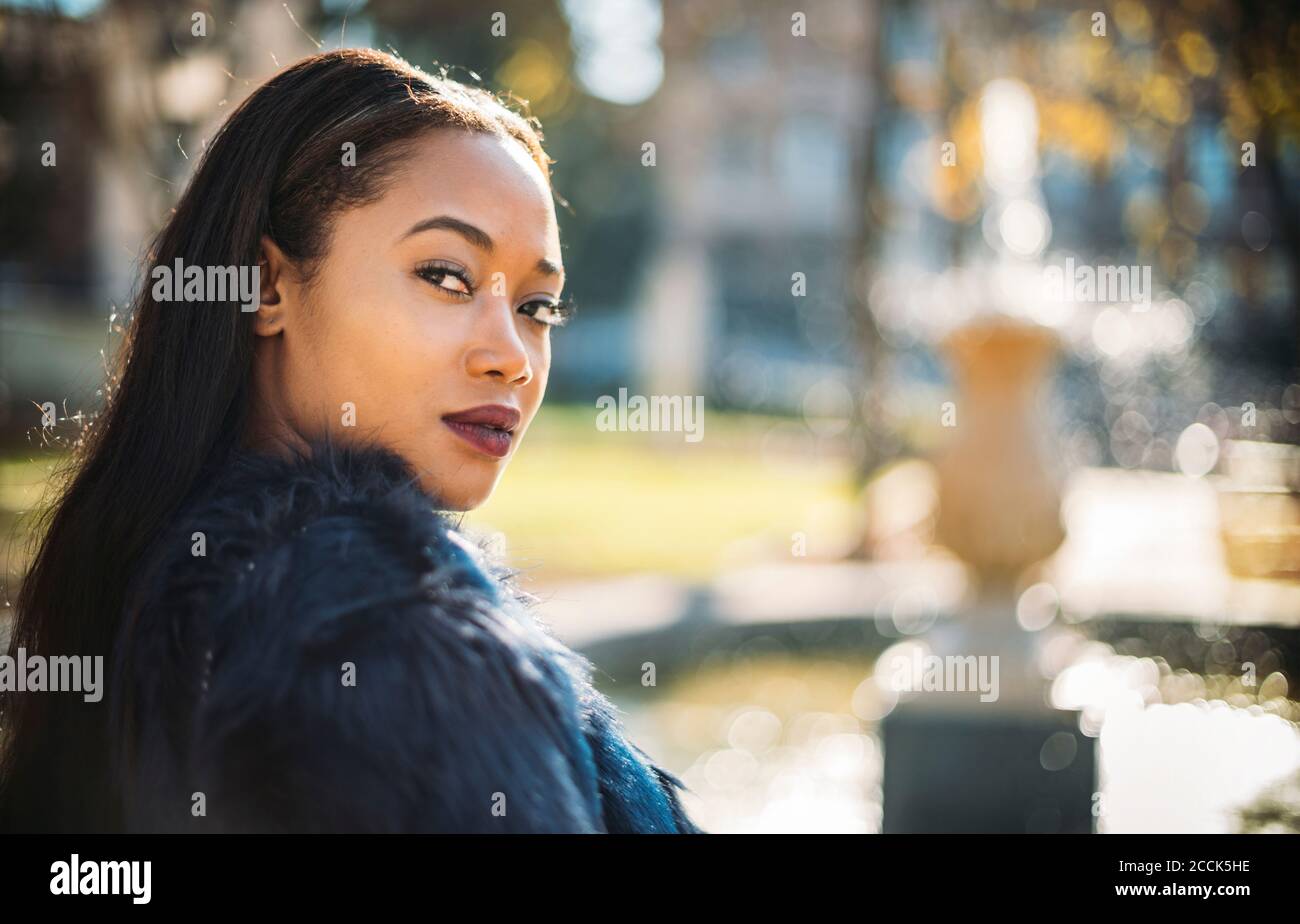 Young woman looking over shoulder outdoors Stock Photo