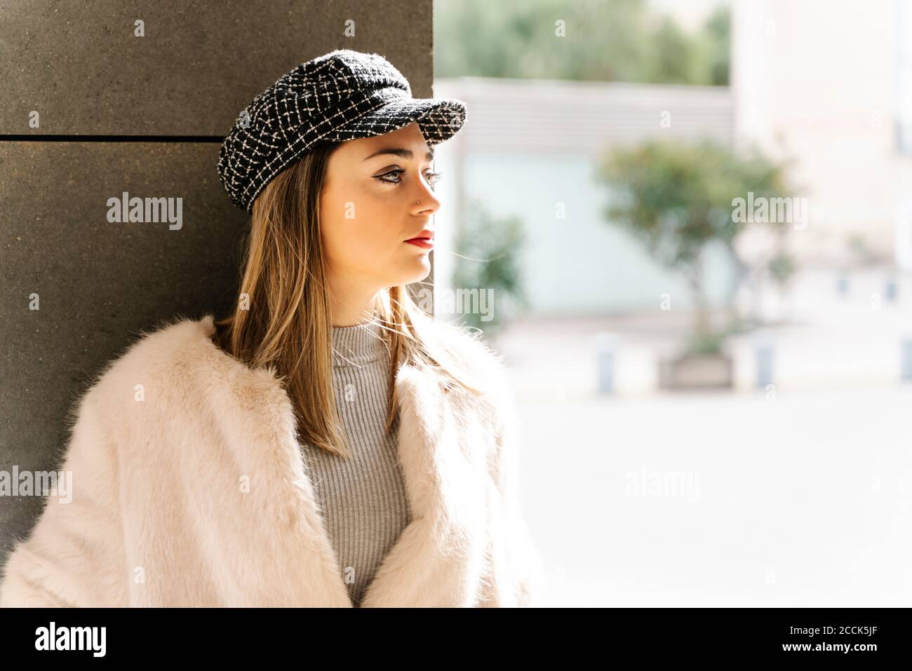 Beautiful woman in jacket looking away against wall Stock Photo