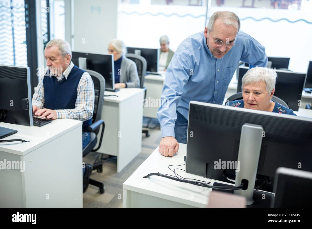 Active seniors attending computer course, intructor giving advice Stock Photo