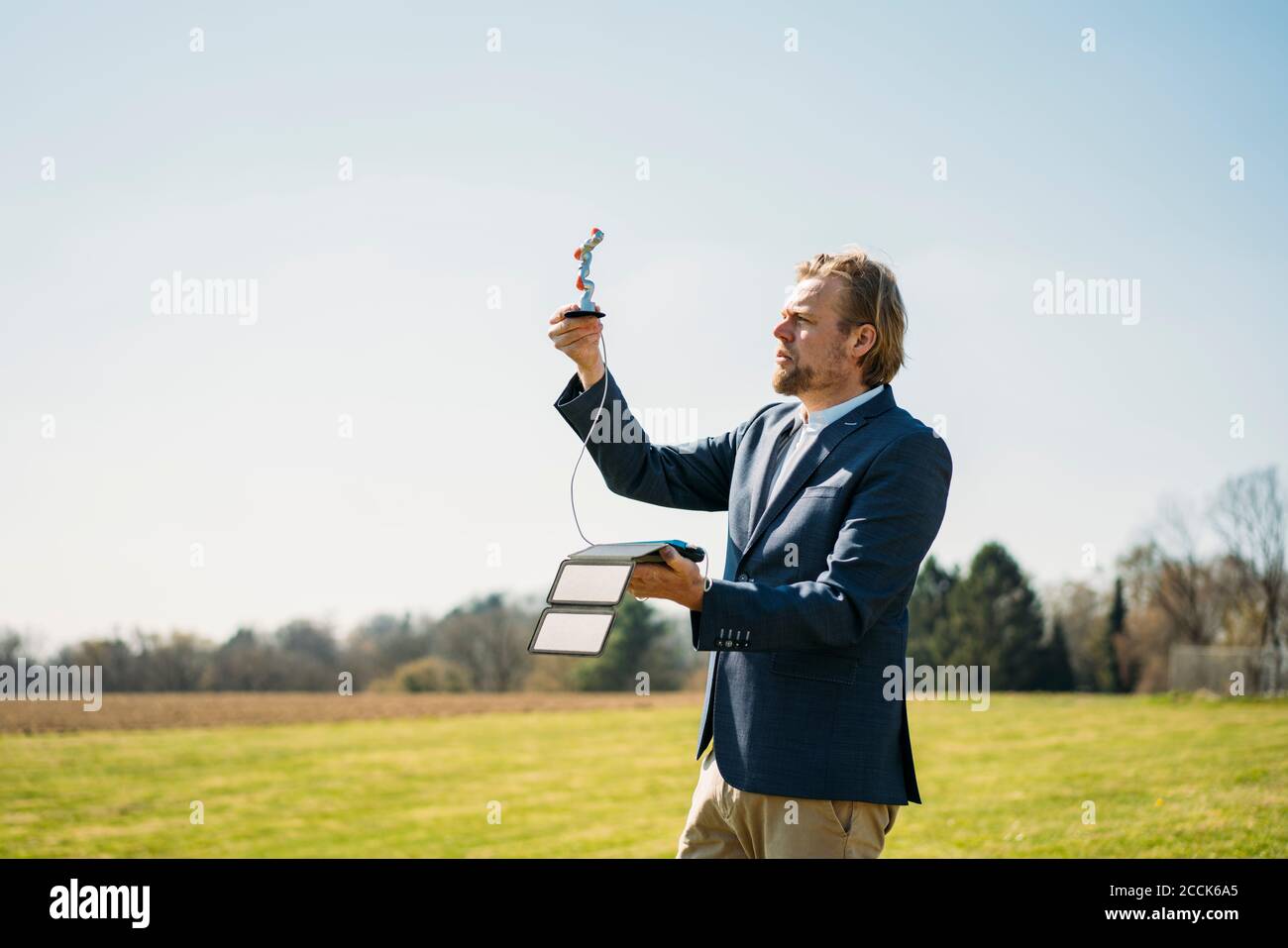 Engineer analyzing robot arm while charging with portable solar panel against clear sky on sunny day Stock Photo