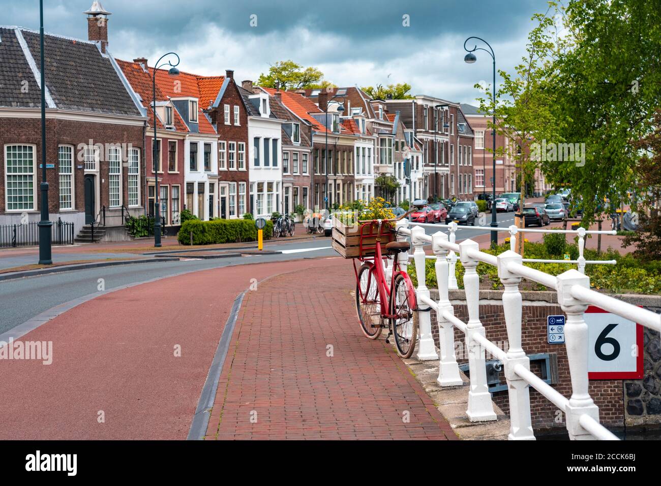 Netherlands, North Holland, Haarlem, Bicycle parked along railing of canal bridge with houses along Hooimarkt street in background Stock Photo