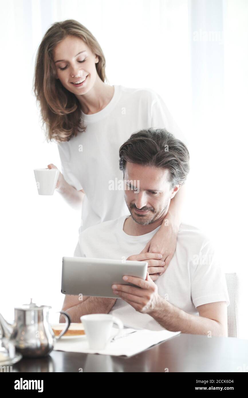 Couple having breakfast at home and using tablet Stock Photo