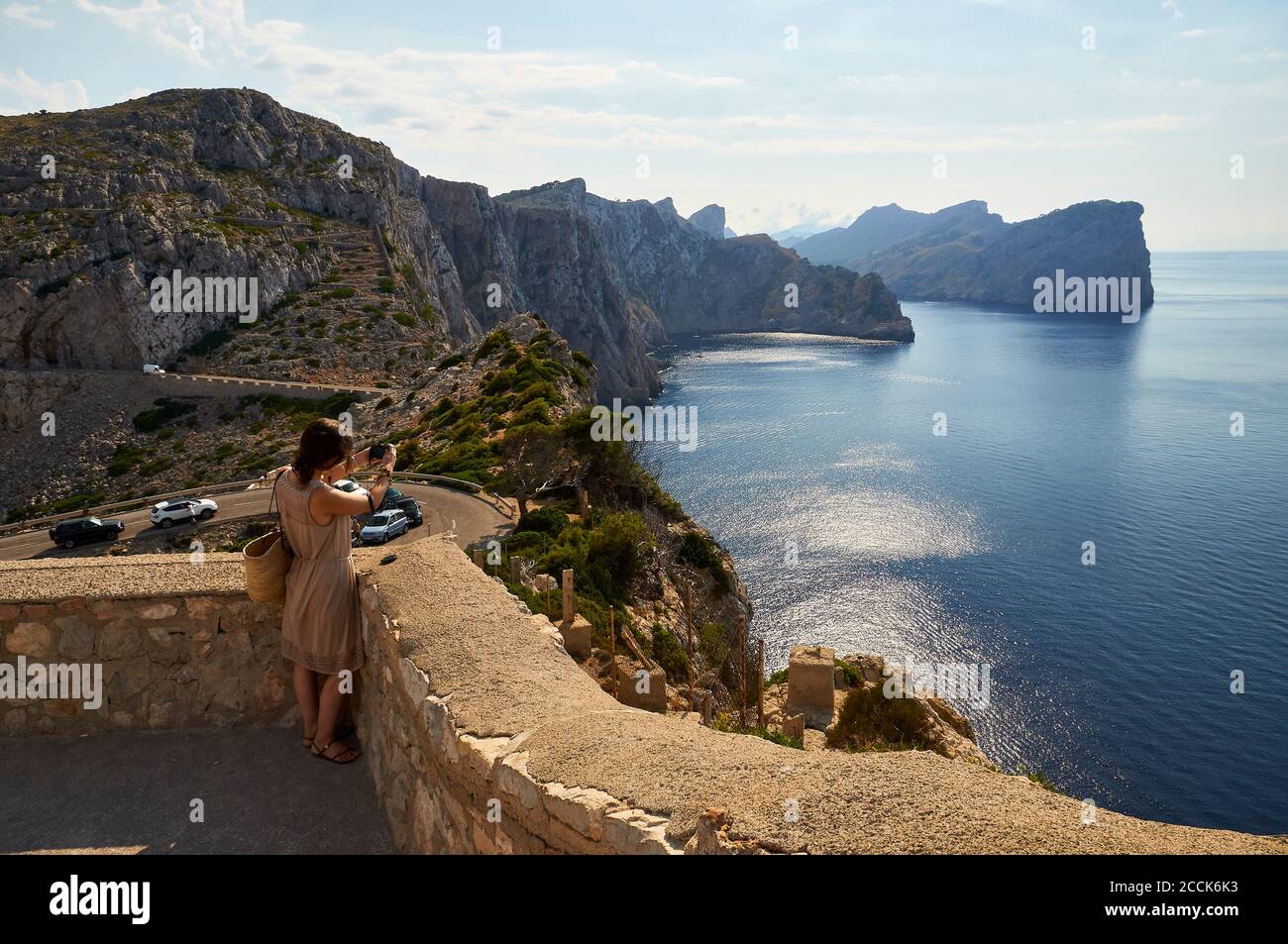 Young woman photographing the Majorcan coastline landscape from Formentor cape (Cap de Formentor, Majorca, Balearic Islands, Mediterranean sea, Spain) Stock Photo