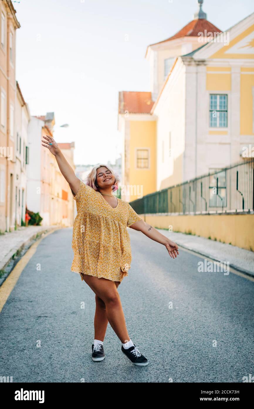 Woman with arms outstretched standing on road in city Stock Photo
