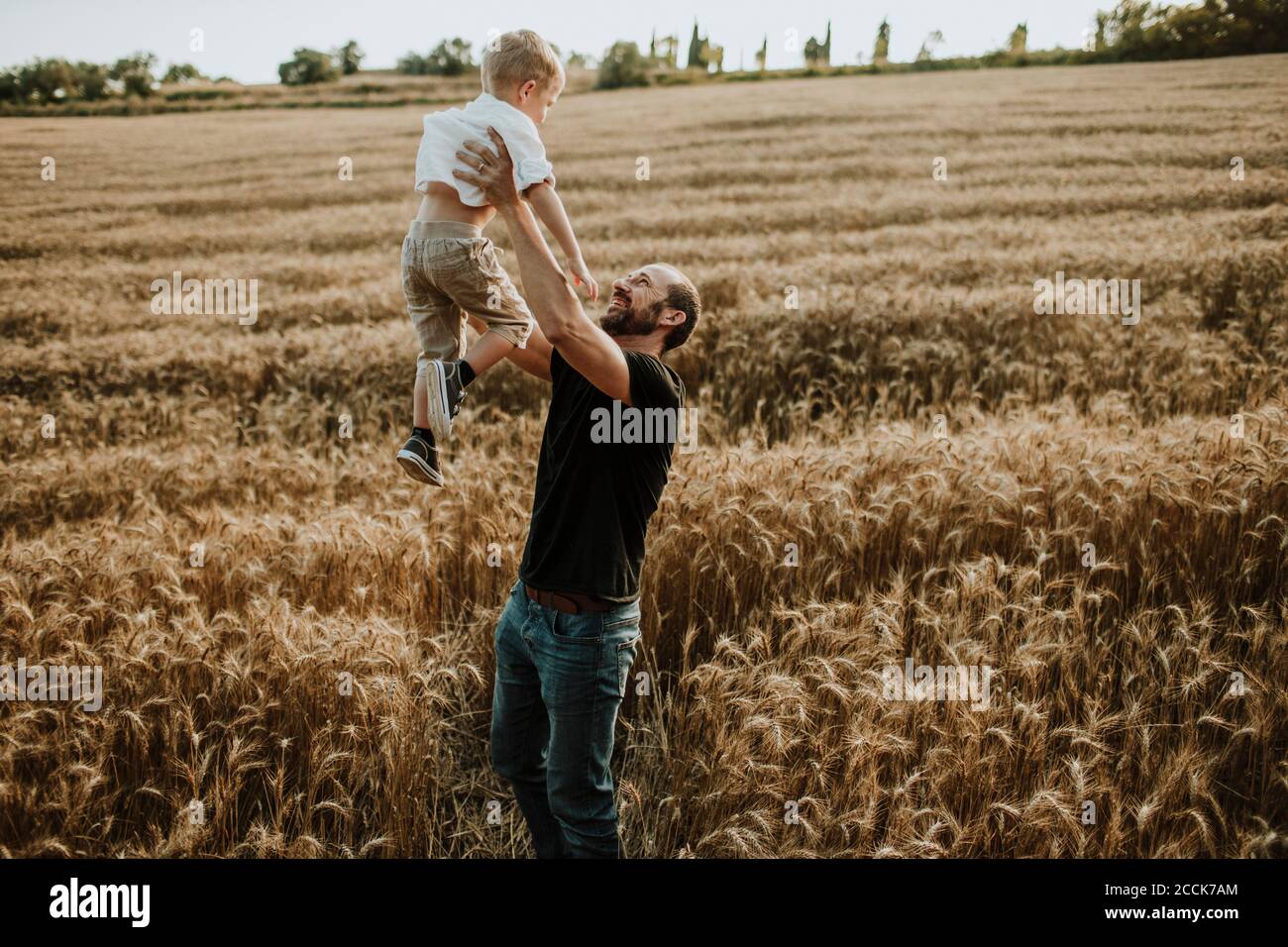Father spending leisure time with son in wheat farm Stock Photo