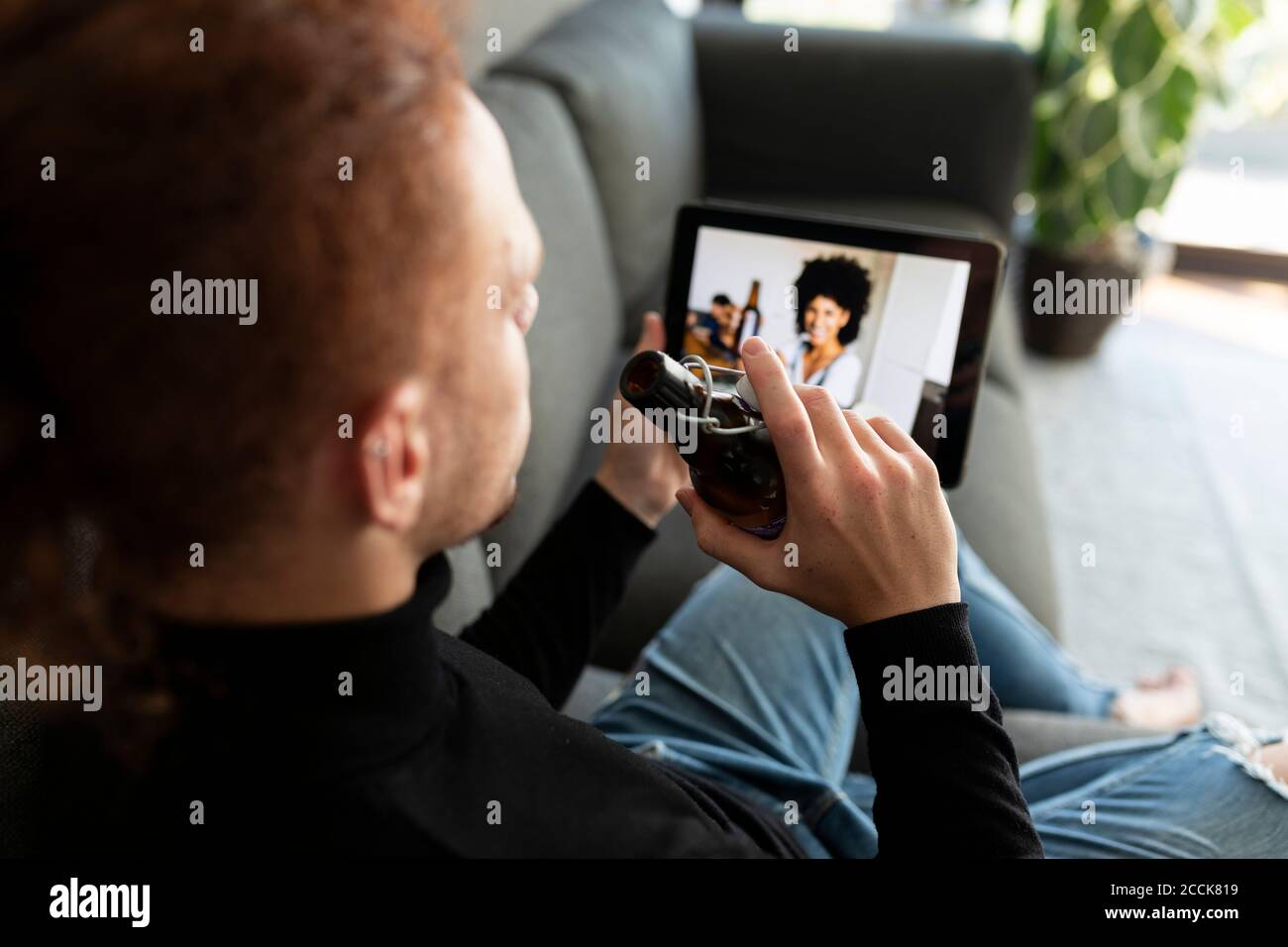 Man using digital tablet while drinking beer at home Stock Photo