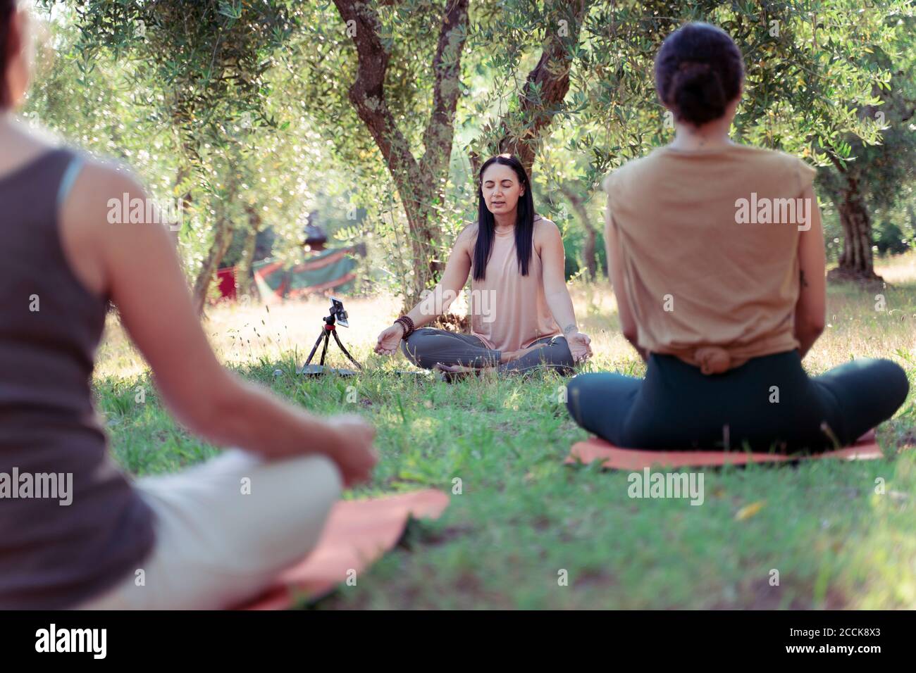 Three people meditating in park Stock Photo