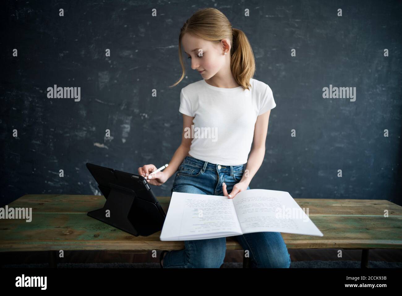 Blond girl learning and using tablet at home Stock Photo