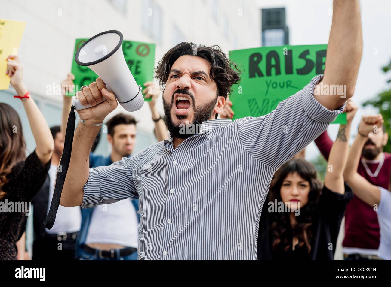 Man holding megaphone screaming with protestors on street Stock Photo