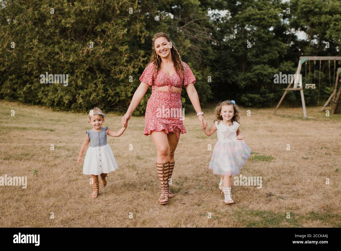 Happy mother walking hand in hand with daughters on a meadow Stock Photo