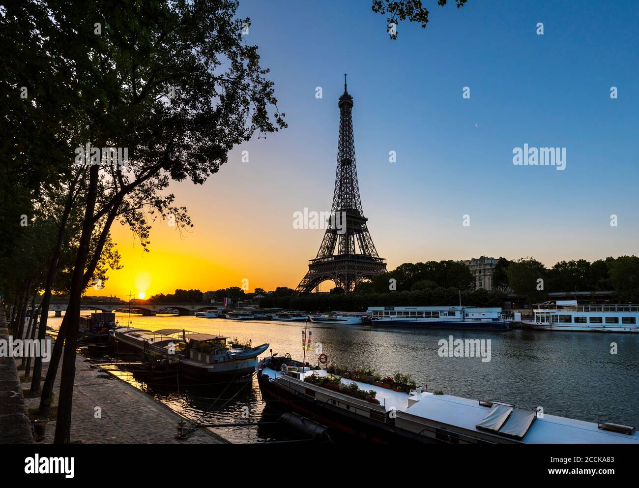 Eiffel Tower by Seine river against clear blue sky during sunrise, Paris, France Stock Photo