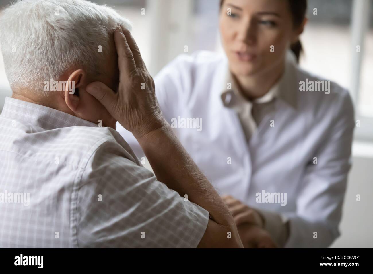 Stressed older senior patient complaining about migraine illness. Stock Photo