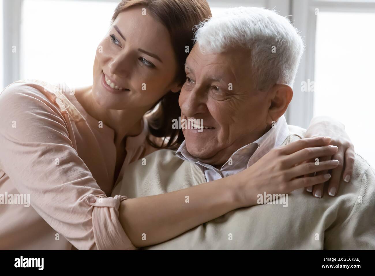 Affectionate young woman cuddling loving positive older retired daddy. Stock Photo