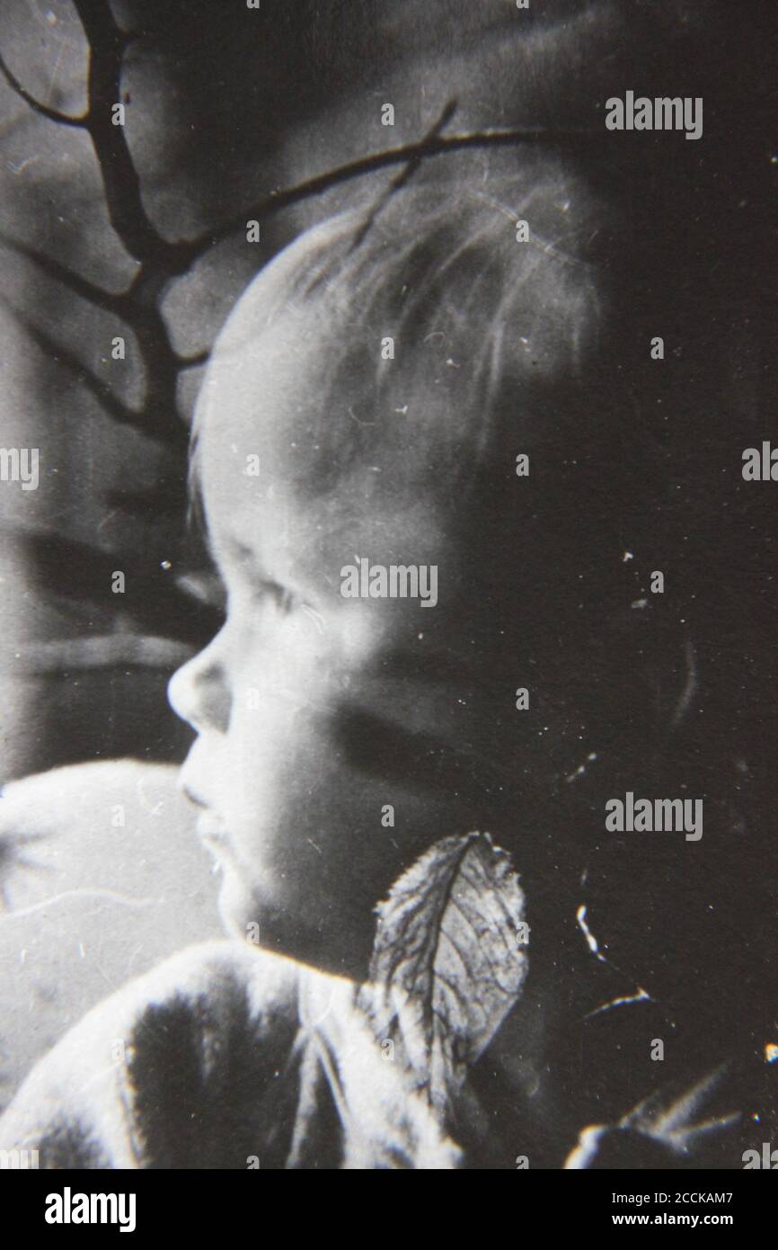 Fine 1970s vintage black and white photography of a little girl staring out of the window. Stock Photo