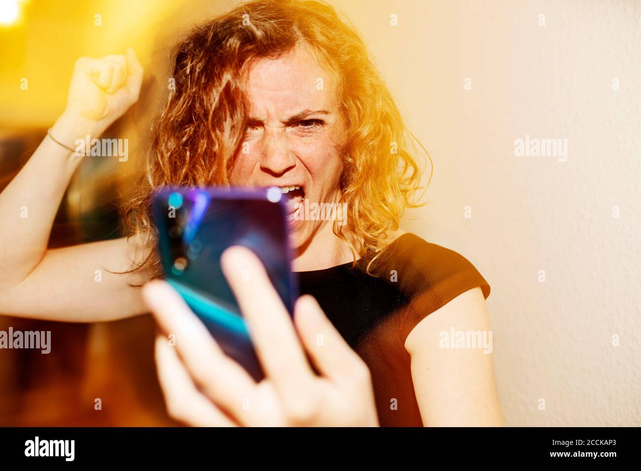 Close-up of woman talking aggressively on video call over smart phone at home Stock Photo