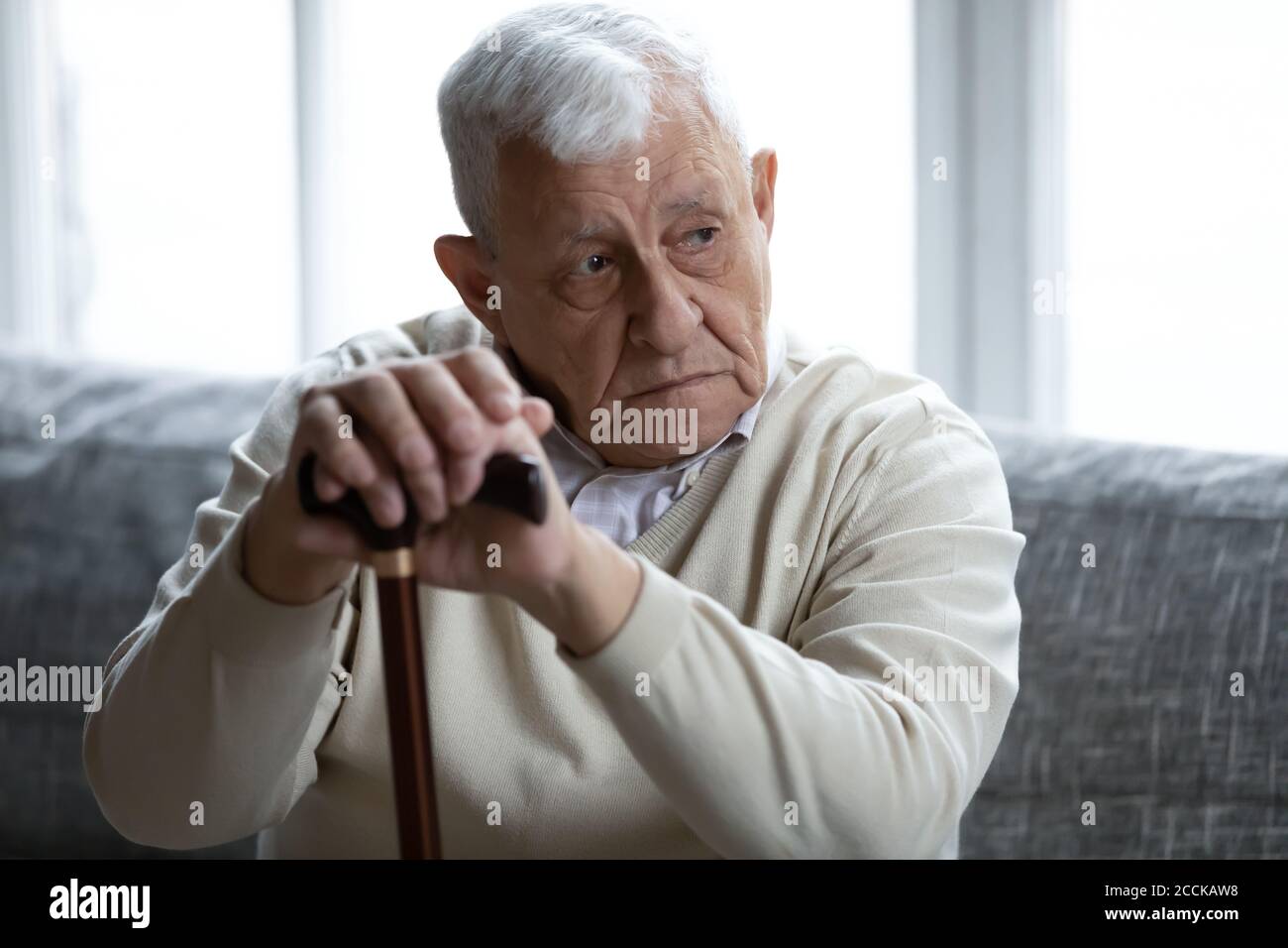 Stressed unhappy older mature grandfather holding hands on wooden stick. Stock Photo