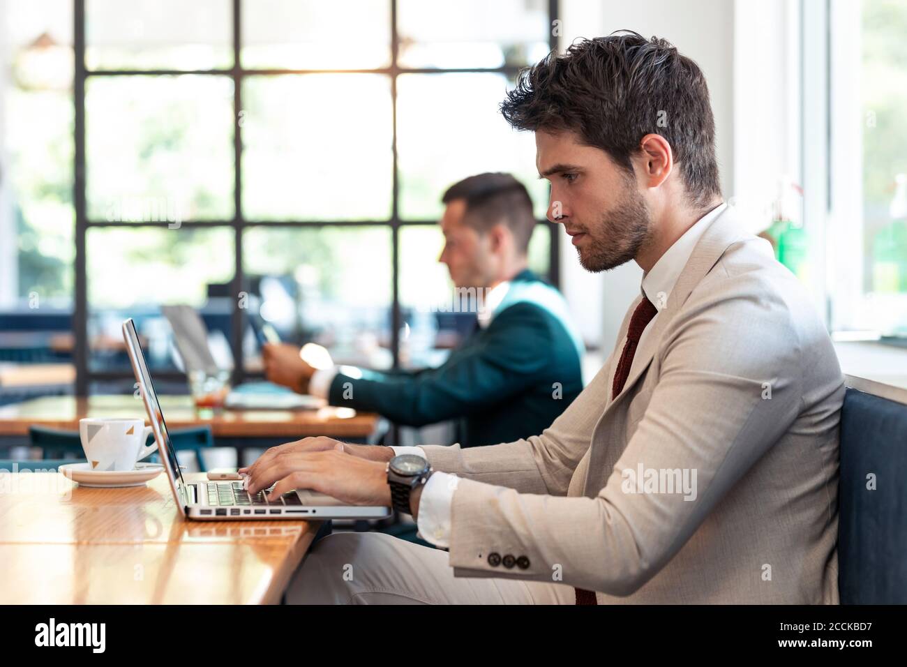 Serious businessman using laptop at table in cafe Stock Photo