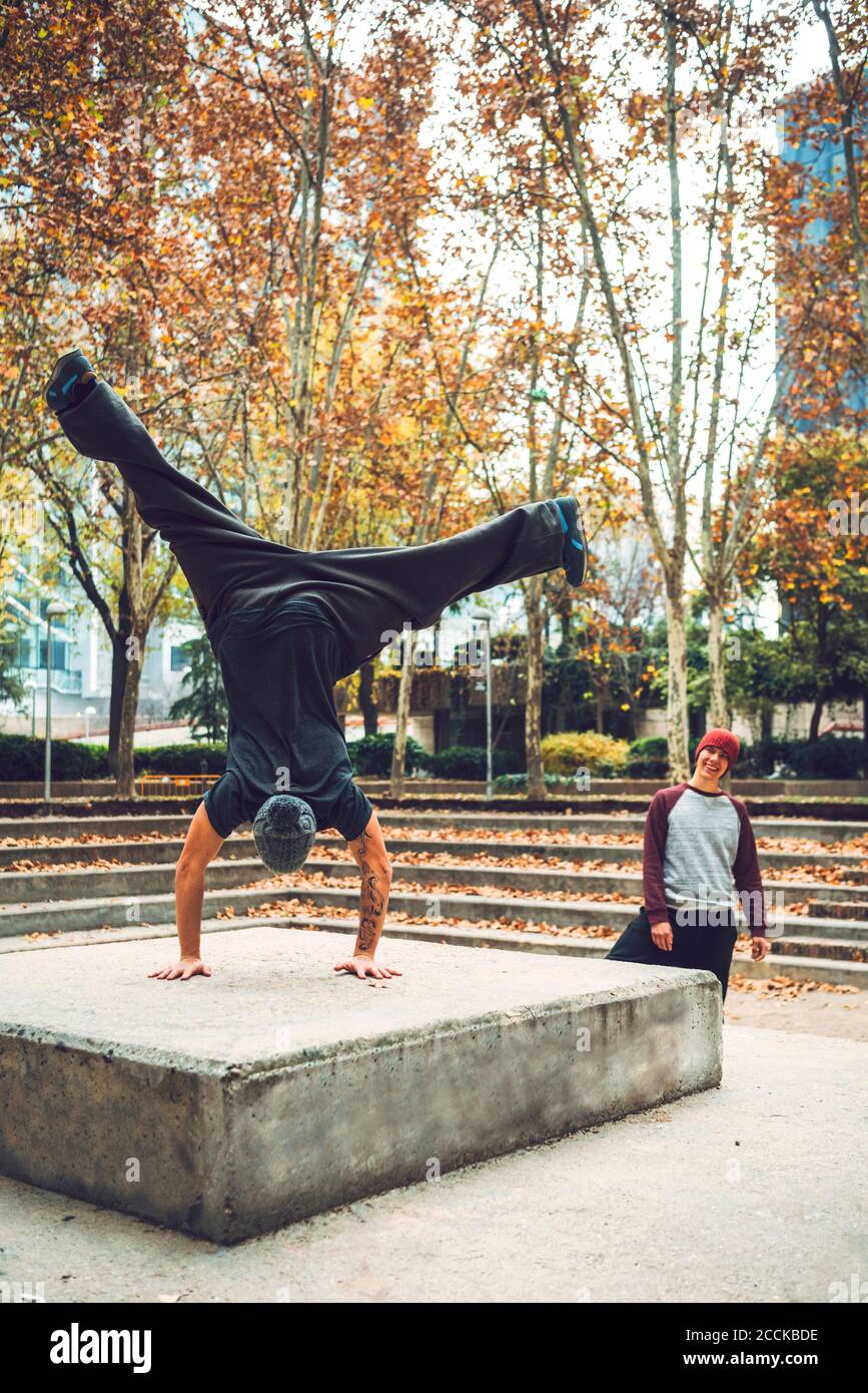 Rear view of male performing handstand by friend in park Stock Photo