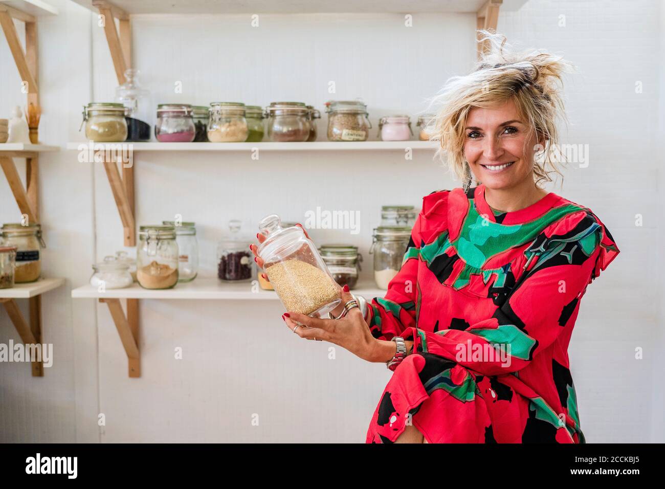 Smiling female cook holding spice container while sitting in cooking class Stock Photo