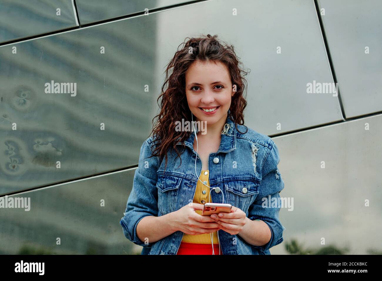 Young woman using smartphone at wall Stock Photo