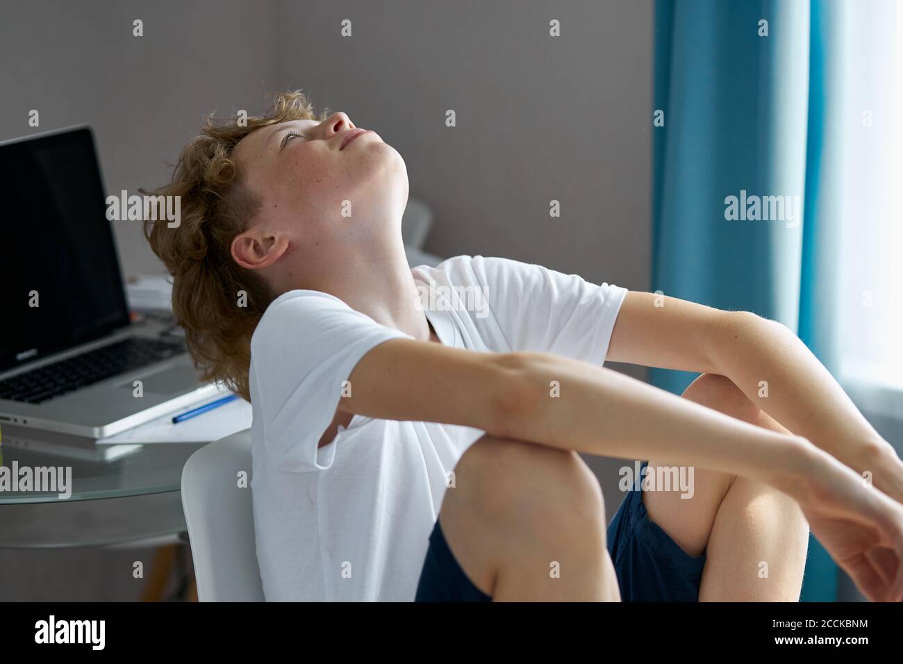 school boy tired to study, to do homework at home, sit depressed and exhausted. at home in bedroom Stock Photo