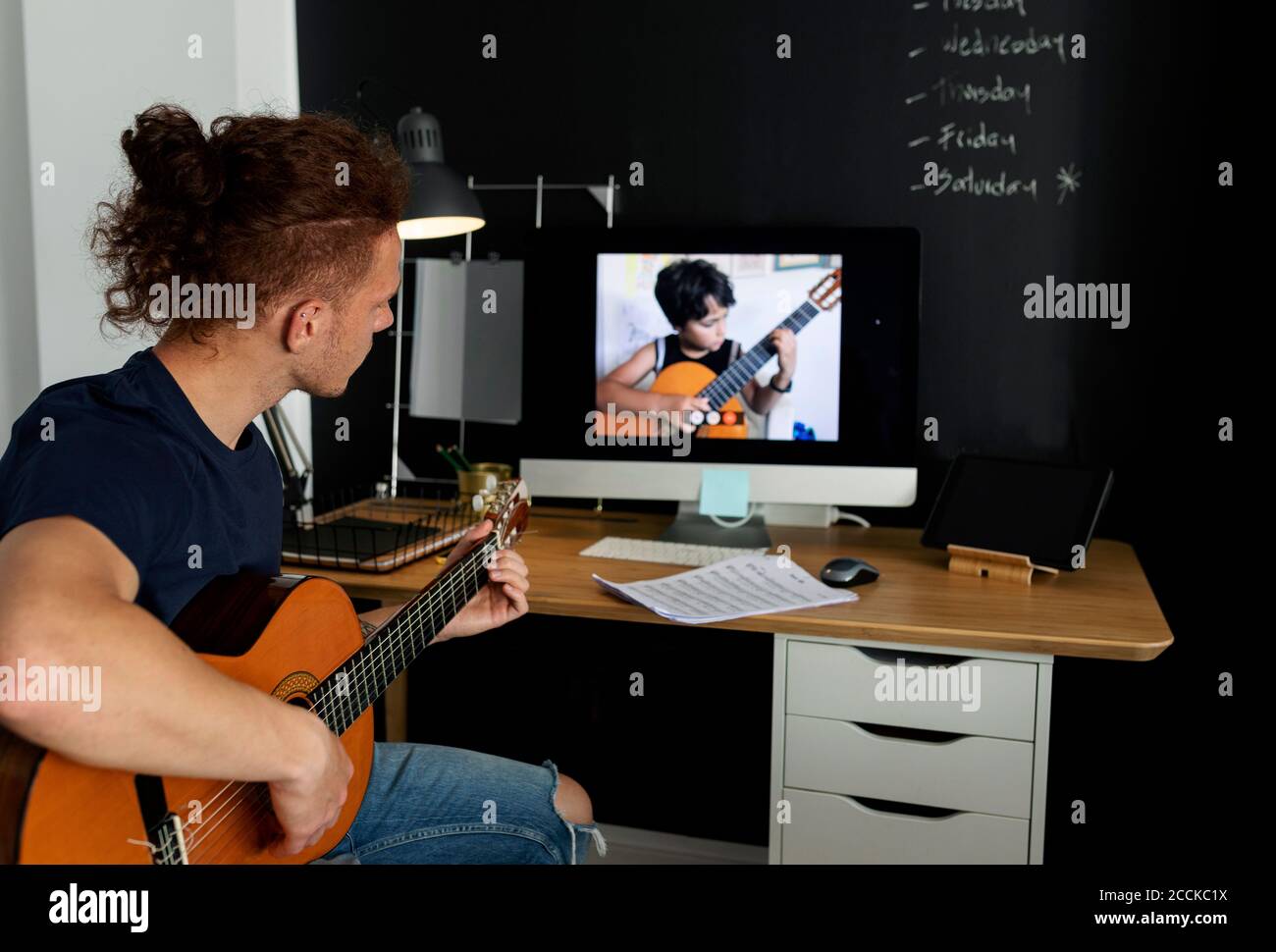 Man learning guitar while watching tutorial at home Stock Photo