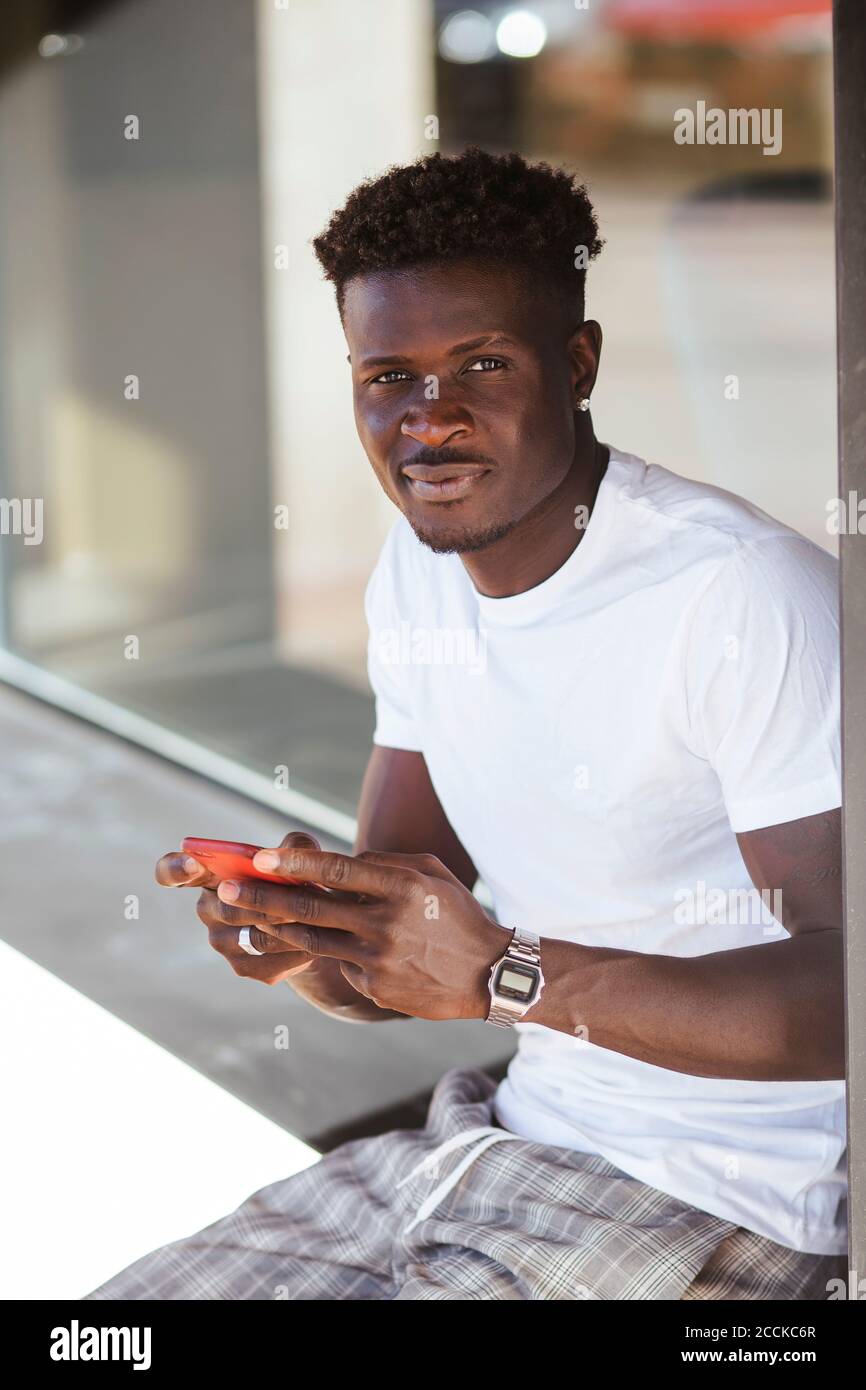 Close-up of young man using smart phone while sitting outdoors Stock Photo