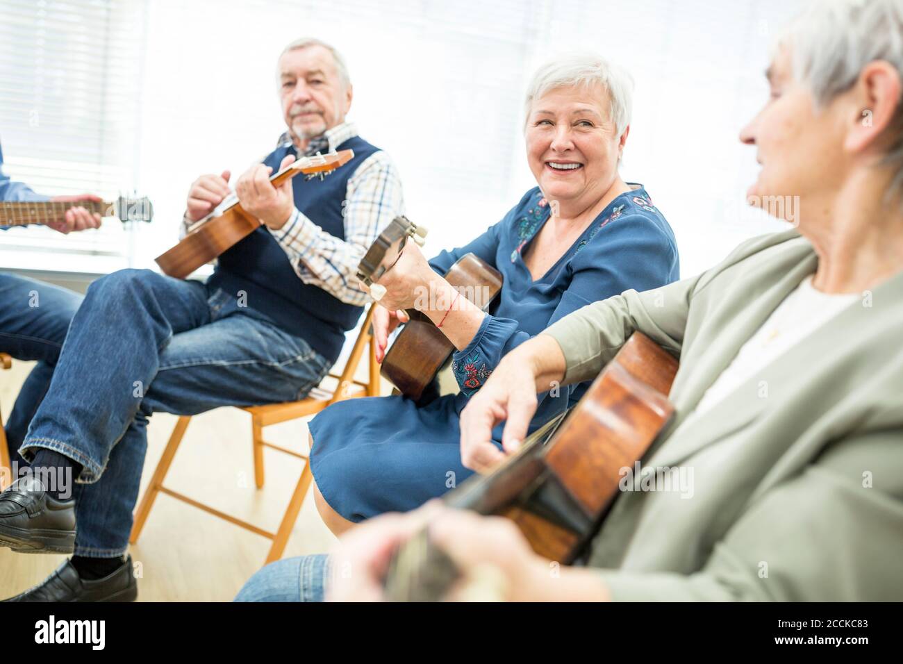 Seniors in retirement home attending guitar class, making music Stock