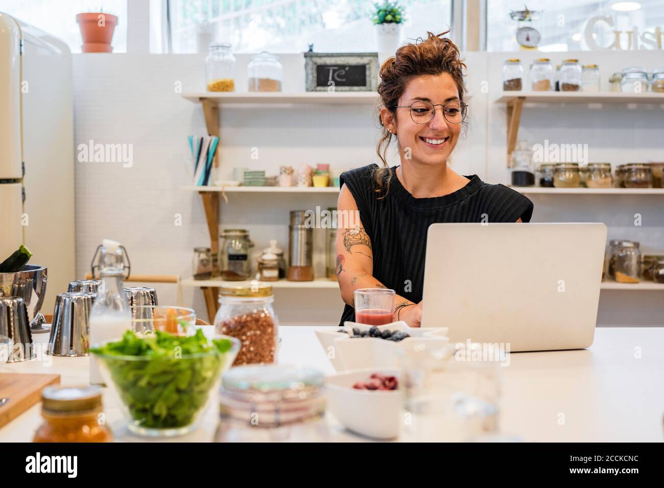 Smiling woman using laptop on kitchen island at cooking school Stock Photo