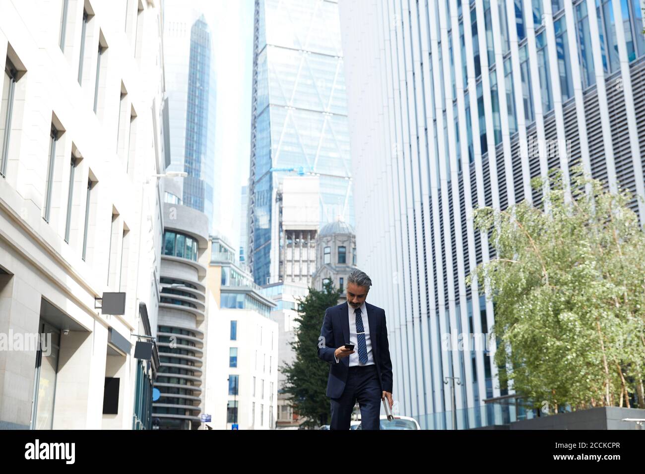 Businessman texting through mobile phone in city Stock Photo